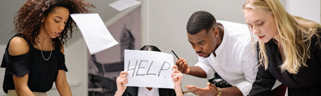 chaotic business meeting with woman holding up sign with help written on it