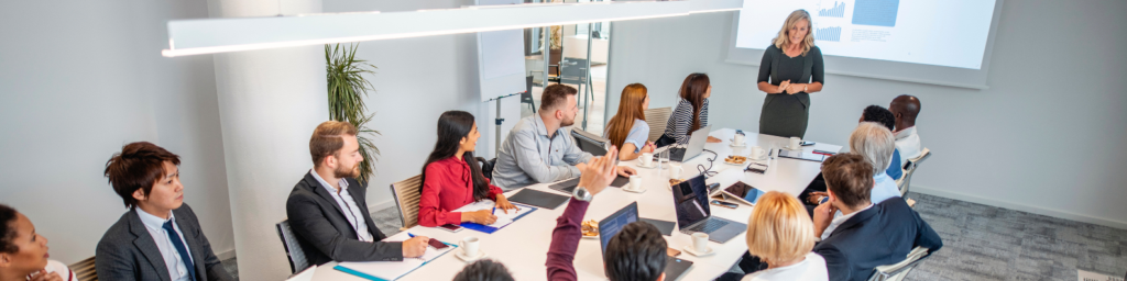 group of diverse executives in a meeting room looking at executive female